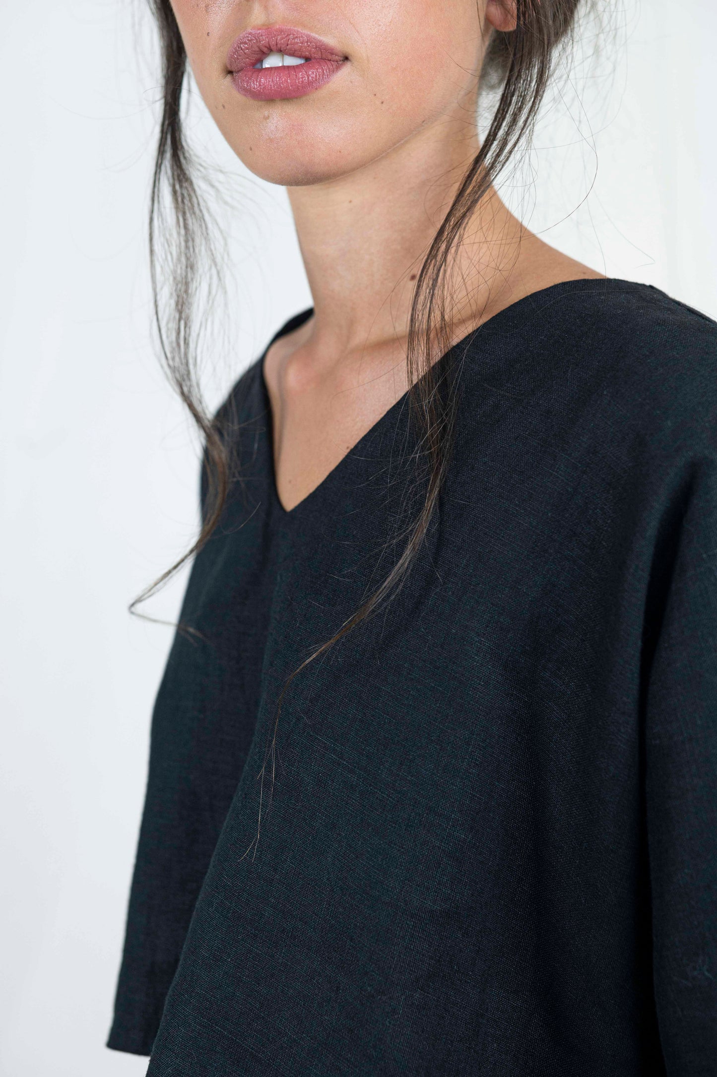 Close up of woman wearing black linen boxy top, softly cropped with a kimono sleeve and v-neck.