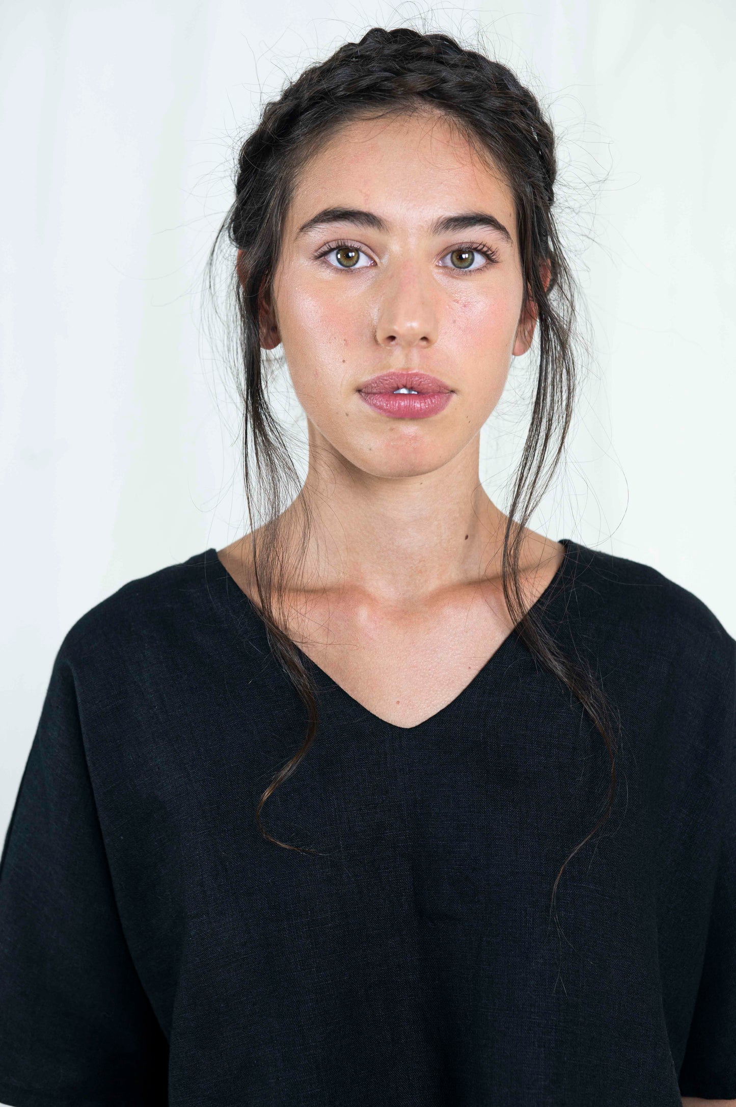 Close up view of woman wearing black linen boxy top, softly cropped with a kimono sleeve and v-neck.